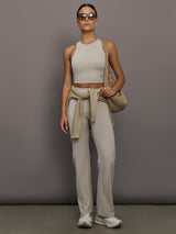 Model wears a high neck sleeveless cropped top in light sandy brown. 