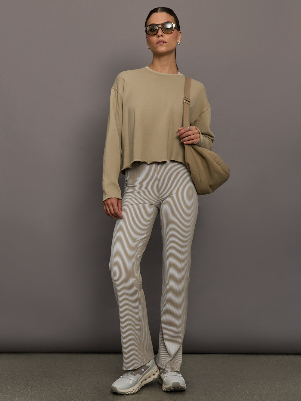 Model wears a pair of high waisted straight leg neutral pinstripe pants. 