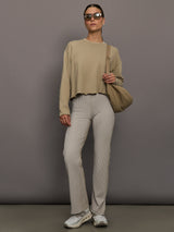 Model wears a pair of high waisted straight leg neutral pinstripe pants. 