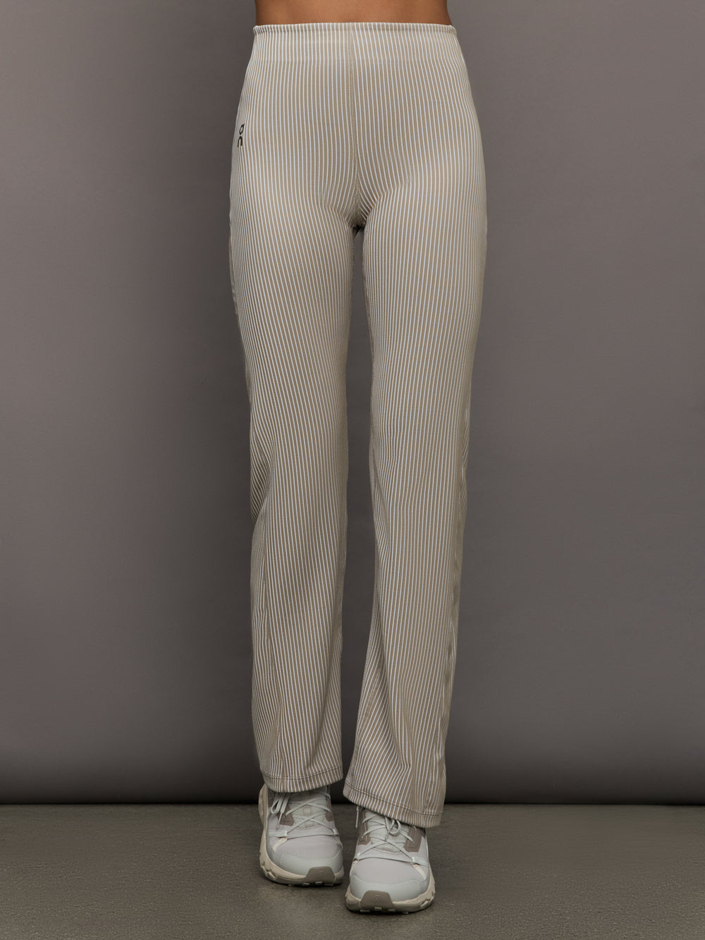 Model wears a pair of high waisted straight leg neutral pinstripe pants. 