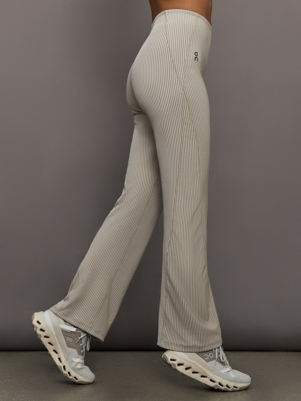 Model wears a pair of high waisted straight leg neutral pinstripe pants. 
