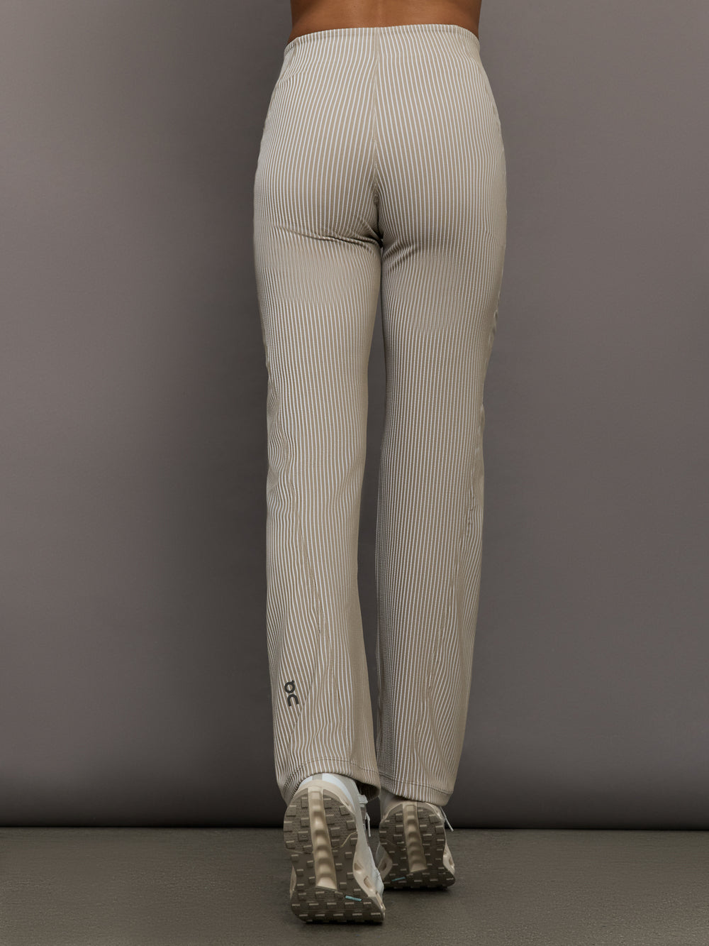 Model wears a pair of high waisted straight leg neutral pinstripe pants. 