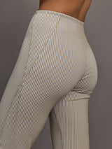 Model wears a pair of high waisted straight leg neutral pinstripe pants. 