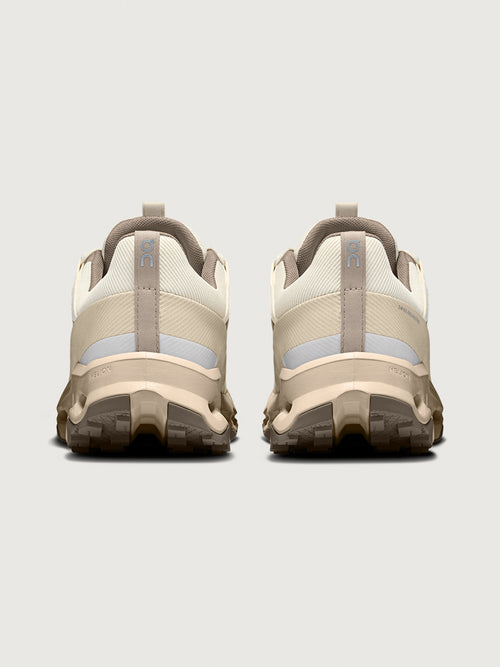 Pair of beige hiking shoes with gray accents on a light gray background