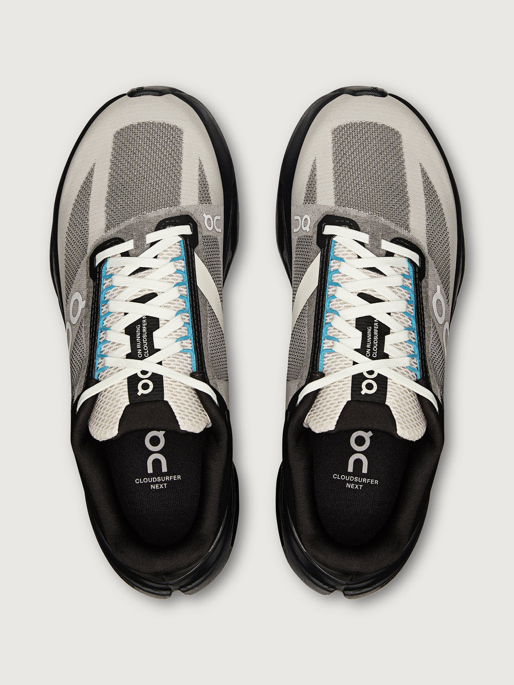 Pair of gray and black running shoes with white laces on a light gray background