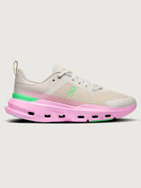 Sneaker with a pink sole and green accents on a white background