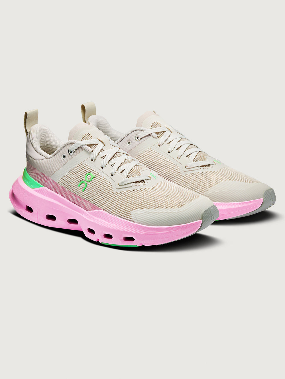Beige and pink sneakers with a green logo on a light gray background