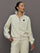 Model wears an off white track jacket with royal blue seam detailing down the sleeves. 