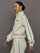 Model wears an off white track jacket with royal blue seam detailing down the sleeves. 