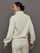 Model wears an off white track jacket with royal blue seam detailing down the sleeves. 