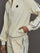 Model wears an off white track jacket with royal blue seam detailing down the sleeves. 