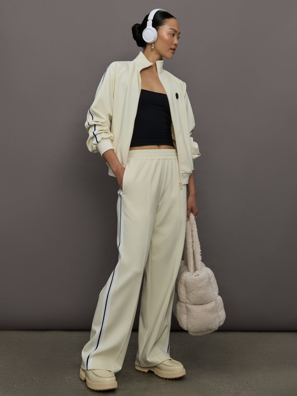 Model wears an off white track jacket with royal blue seam detailing down the sleeves. 