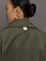 Model wears an olive colored cropped bomber with symmetrical chest pockets and white seamed detailing. 