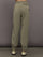 Model wears khaki track pant with large front pockets and cuffed ankles. 