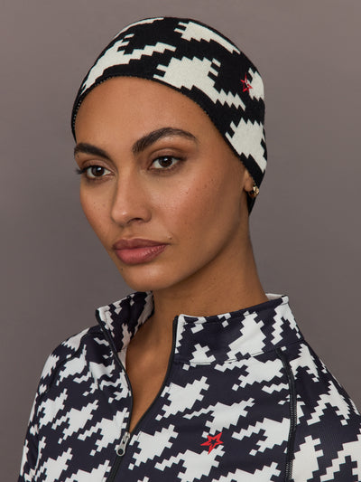 Front view of model in black and white houndstooth merino wool headband styled with matching quarter zip base layer.