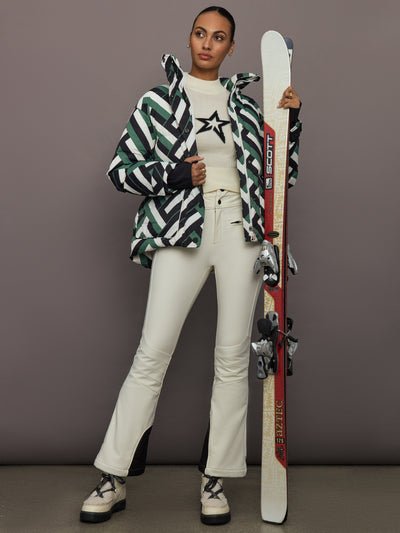 Full body view of Cortina Ski Parka Waffle Print Green styled with snow pants and ski boots.