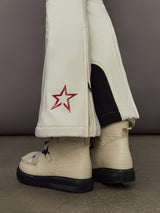 Hem detail of Aurora High Waist Ski Pant Snow White with zip opening and red star logo near ankle.