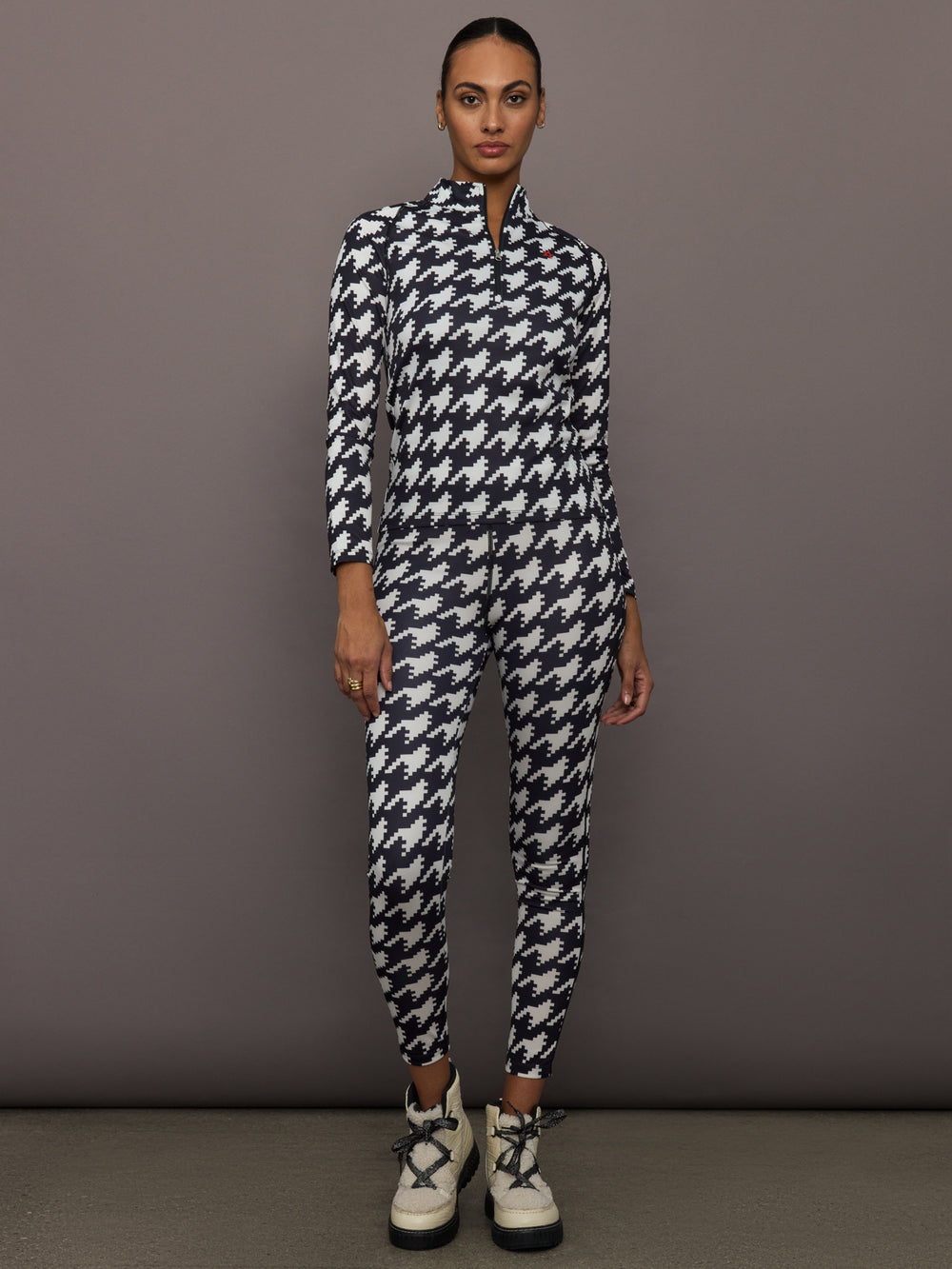 Full body view of model styled in 1/4 Zip Base Layer Top black and white houndstooth with matching leggings.