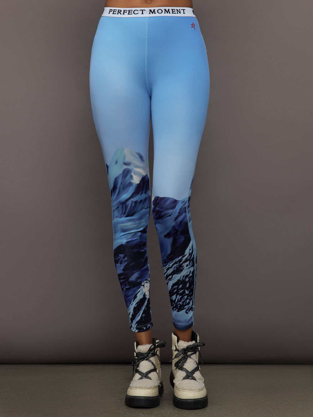 Front view of model wearing Printed Base Layer Leggings in Ski Lift Blue with mountain graphic design.