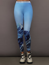 Front view of model wearing Printed Base Layer Leggings in Ski Lift Blue with mountain graphic design.