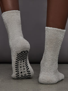 Model is wearing Happy Cloud Plush Grip Crew Sock in Heather Grey, back view.