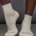 Model is wearing Mental Vacay Grip Ankle Sock in Ivory, front view.