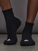 Model is wearing Love Grip Ankle Sock in Black, front view.