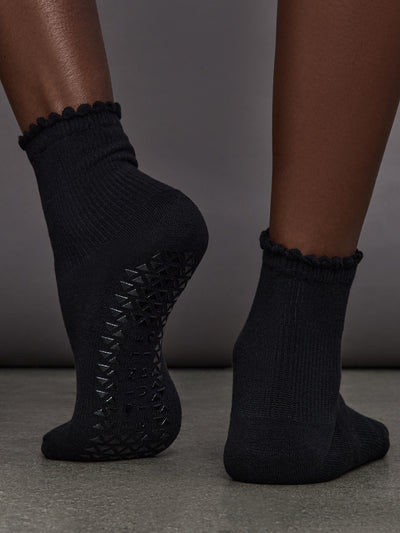 Model is wearing Love Grip Ankle Sock in Black, back view with grip sole detail.