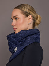 Woman wearing a blue quilted scarf against a gray background