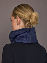 Person wearing a navy quilted jacket with a plain background