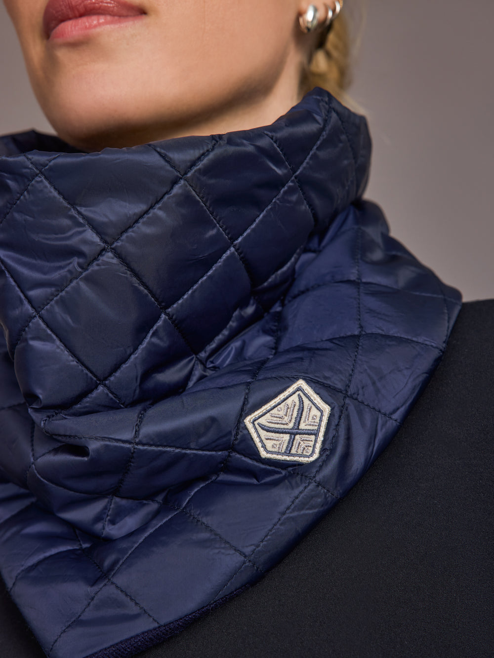 Navy quilted scarf with a brand logo worn by a person