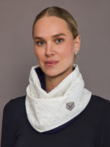 Woman wearing a white quilted scarf with a brand logo against a gray background