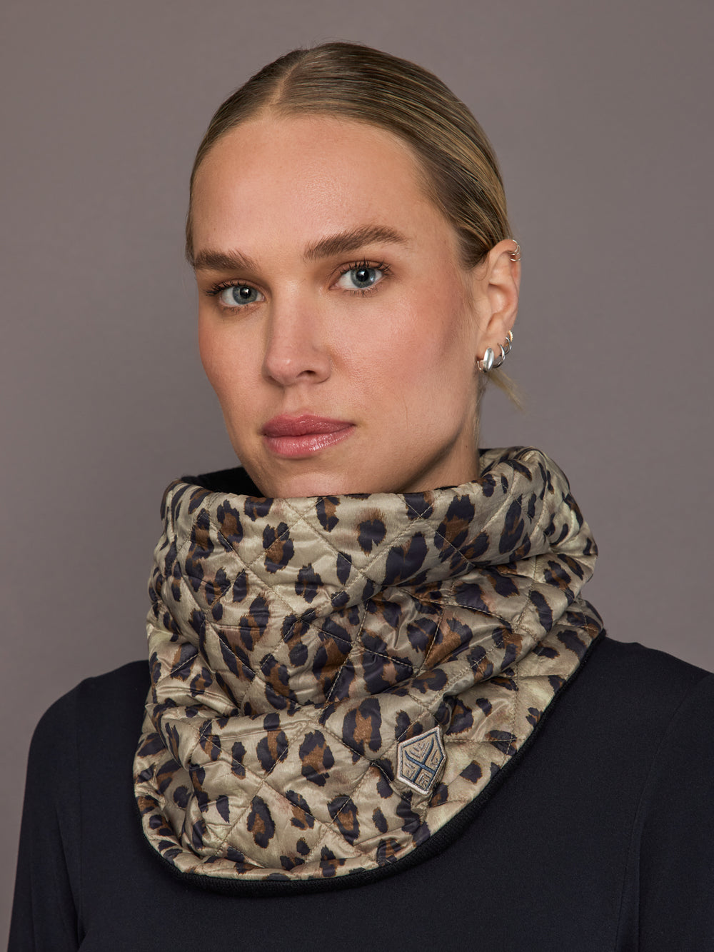 Woman wearing a leopard print scarf against a gray background