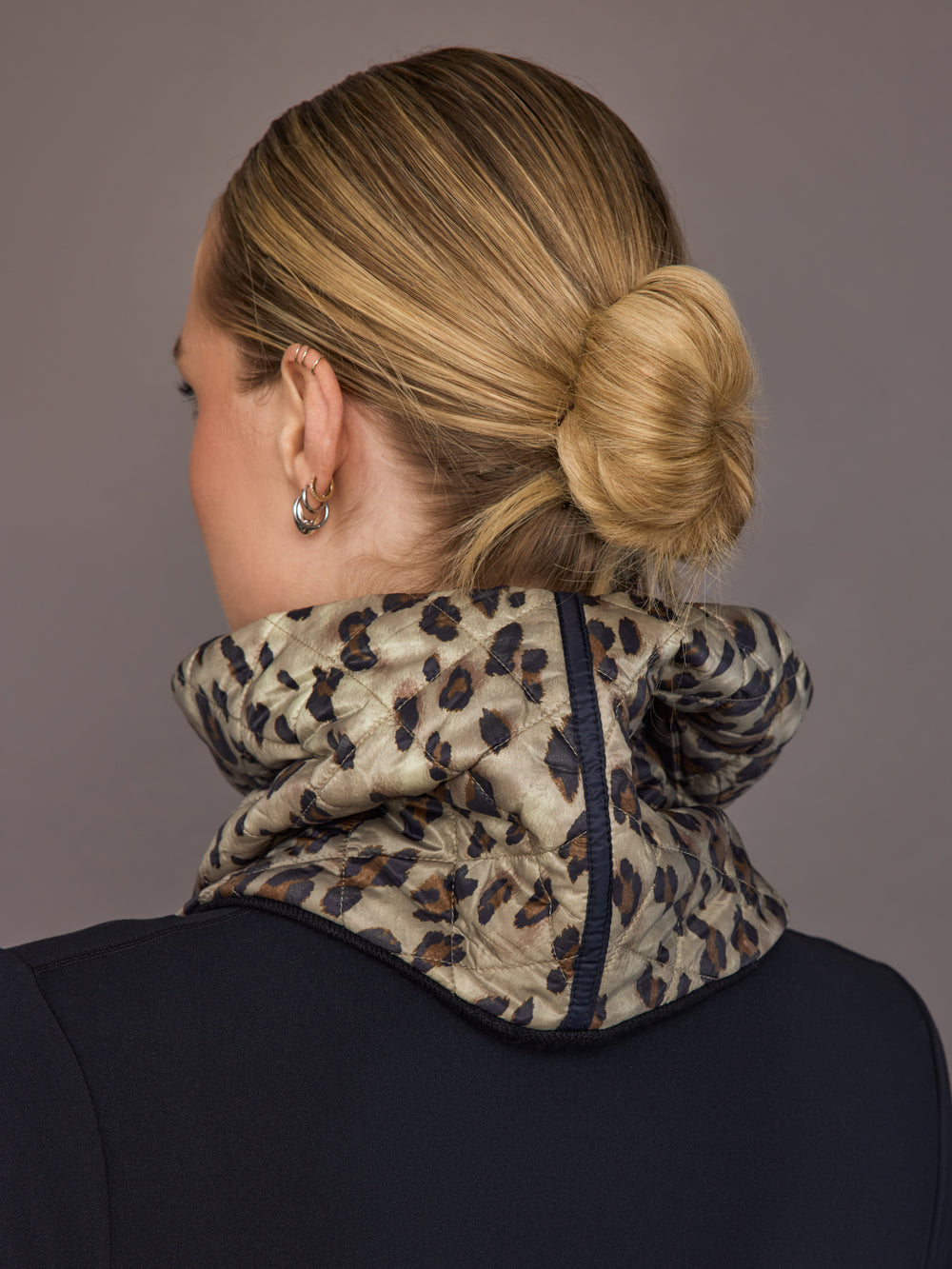 Person wearing a leopard print scarf with a plain background