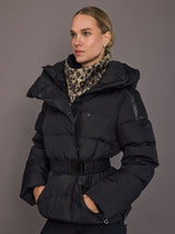 Woman wearing a black puffer jacket with a leopard print scarf against a gray background
