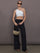Model is wearing Palazzo Pant in Melt in black, styled with one shoulder white crop top and black slides.