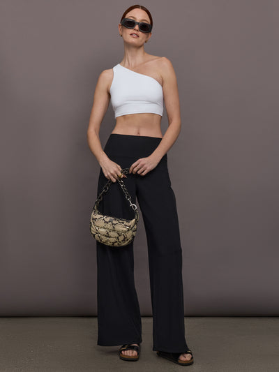 Model is wearing Palazzo Pant in Melt in black, styled with one shoulder white crop top and black slides.