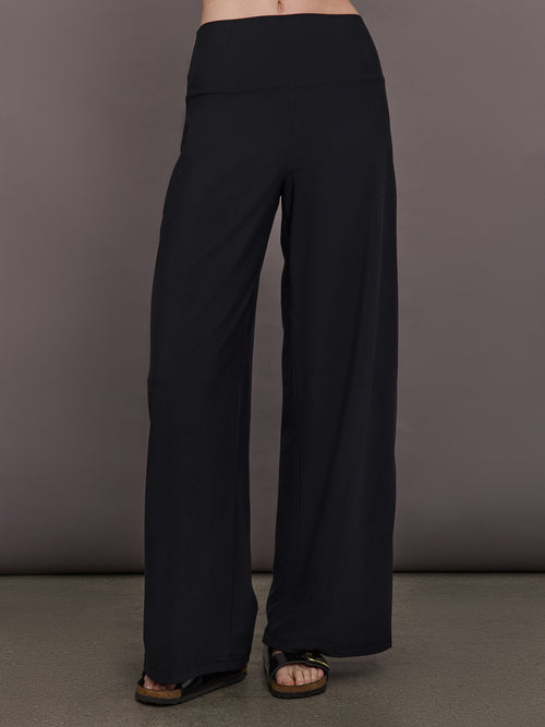 Model is wearing Palazzo Pant in Melt in black, front full length view with wide leg silhouette and high rise waistband.