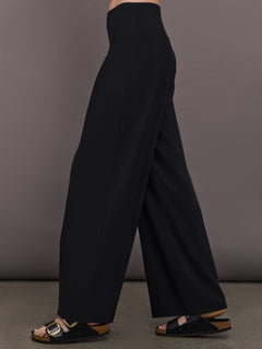 Model is wearing Palazzo Pant in Melt in black, side view highlighting fluid drape and relaxed palazzo leg.