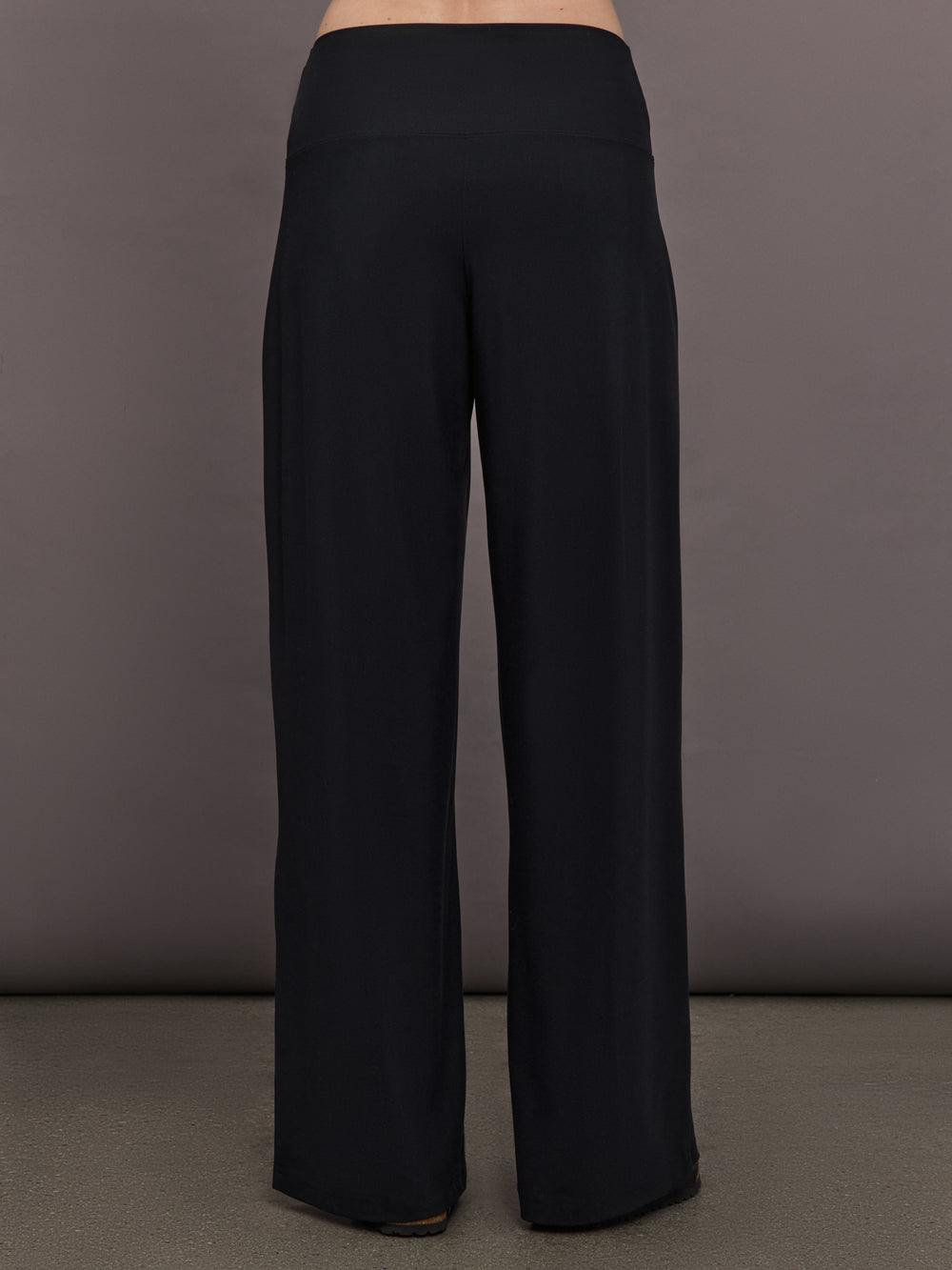 Model is wearing Palazzo Pant in Melt in black, back view showcasing wide leg shape and clean waistband construction.