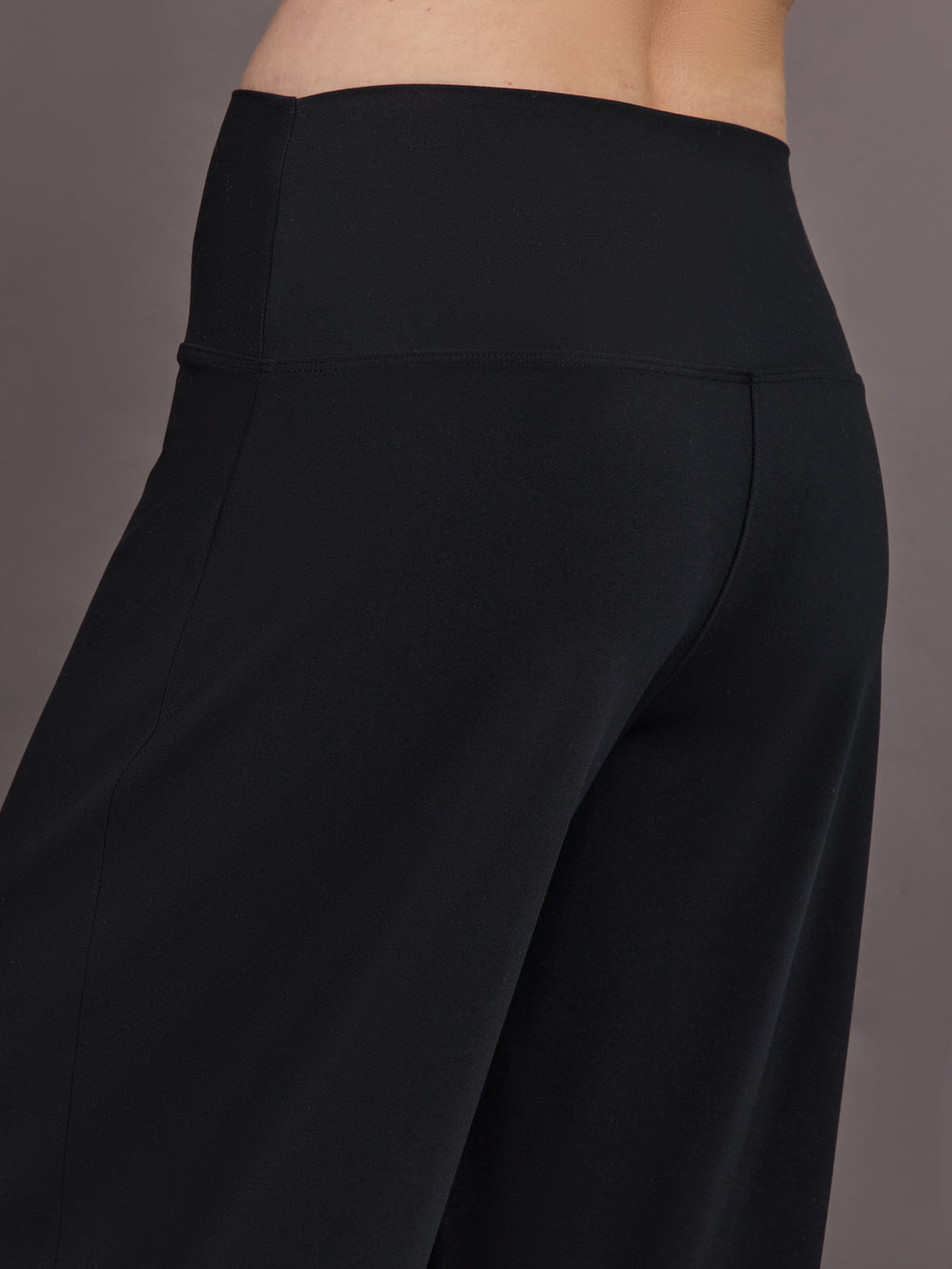 Model is wearing Palazzo Pant in Melt in black, angled back close-up of waistband and seam detailing.