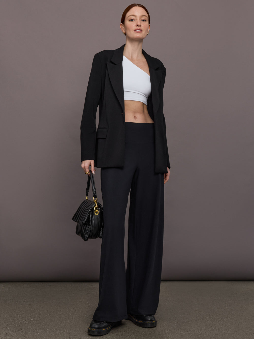 Model is wearing Palazzo Pant in Melt in black, styled with black blazer and cropped top for elevated look.