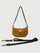 Brown suede handbag with a black strap on a light gray background