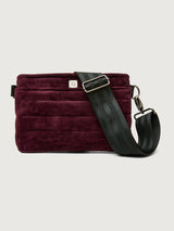 Burgundy suede handbag with a black seat belt strap 