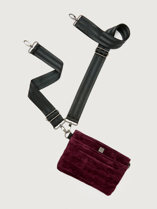 Burgundy suede handbag with a black seat belt strap 