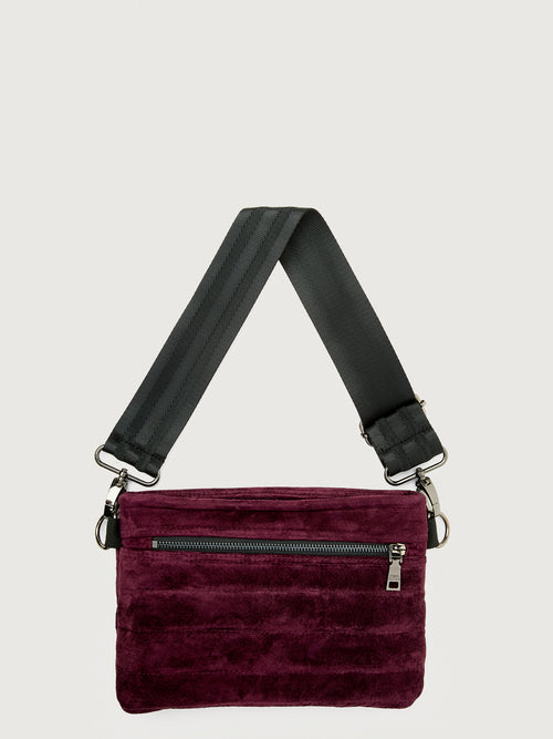 Burgundy suede handbag with a black seat belt strap 