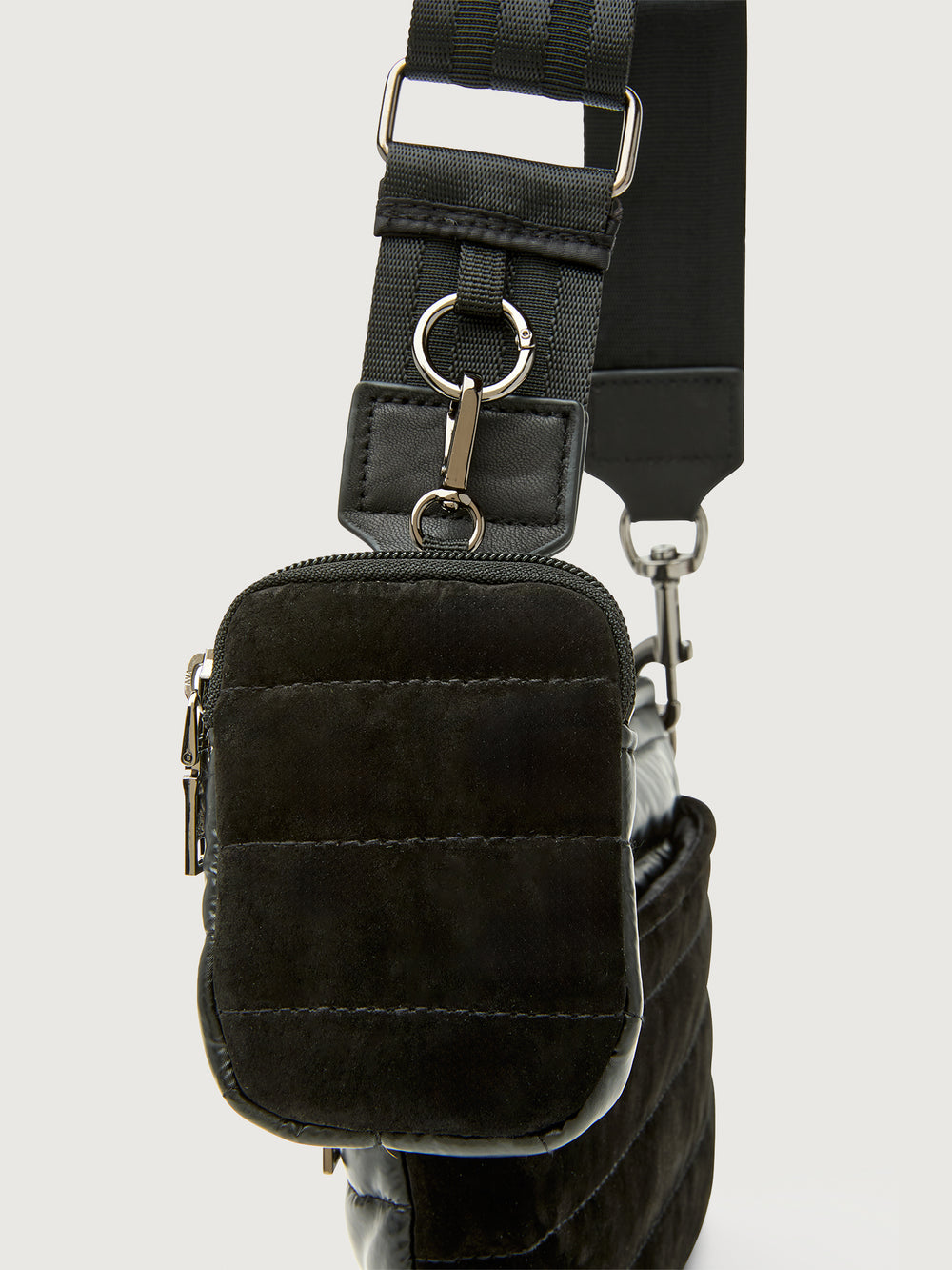 Black crossbody bag with adjustable strap on a light gray background