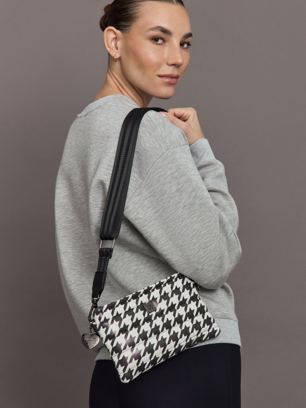 Model wearing Fame Bag Houndstooth Black crossbody style with black web strap.