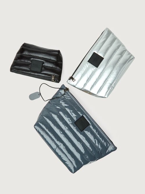 Set of three bags including a black pouch, a silver metallic bag, and a gray striped bag on a light gray background.
