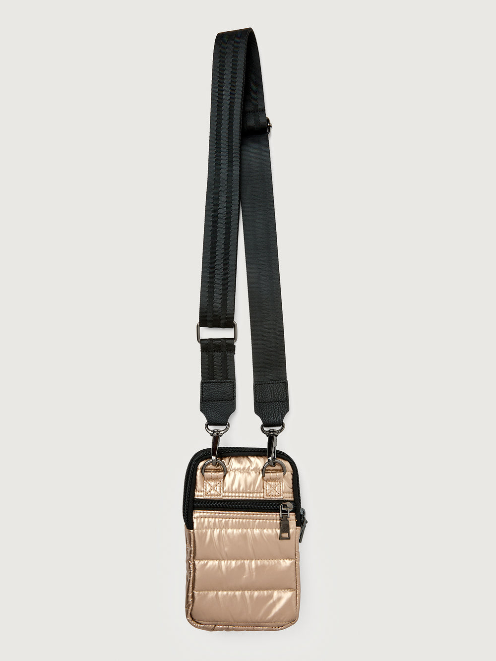 Gold crossbody bag with a black strap on a light gray background